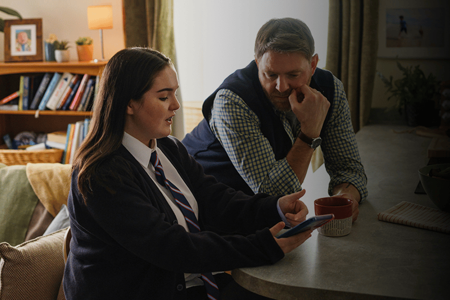 Image from DfE campaign. Shows male adult helping child with phone